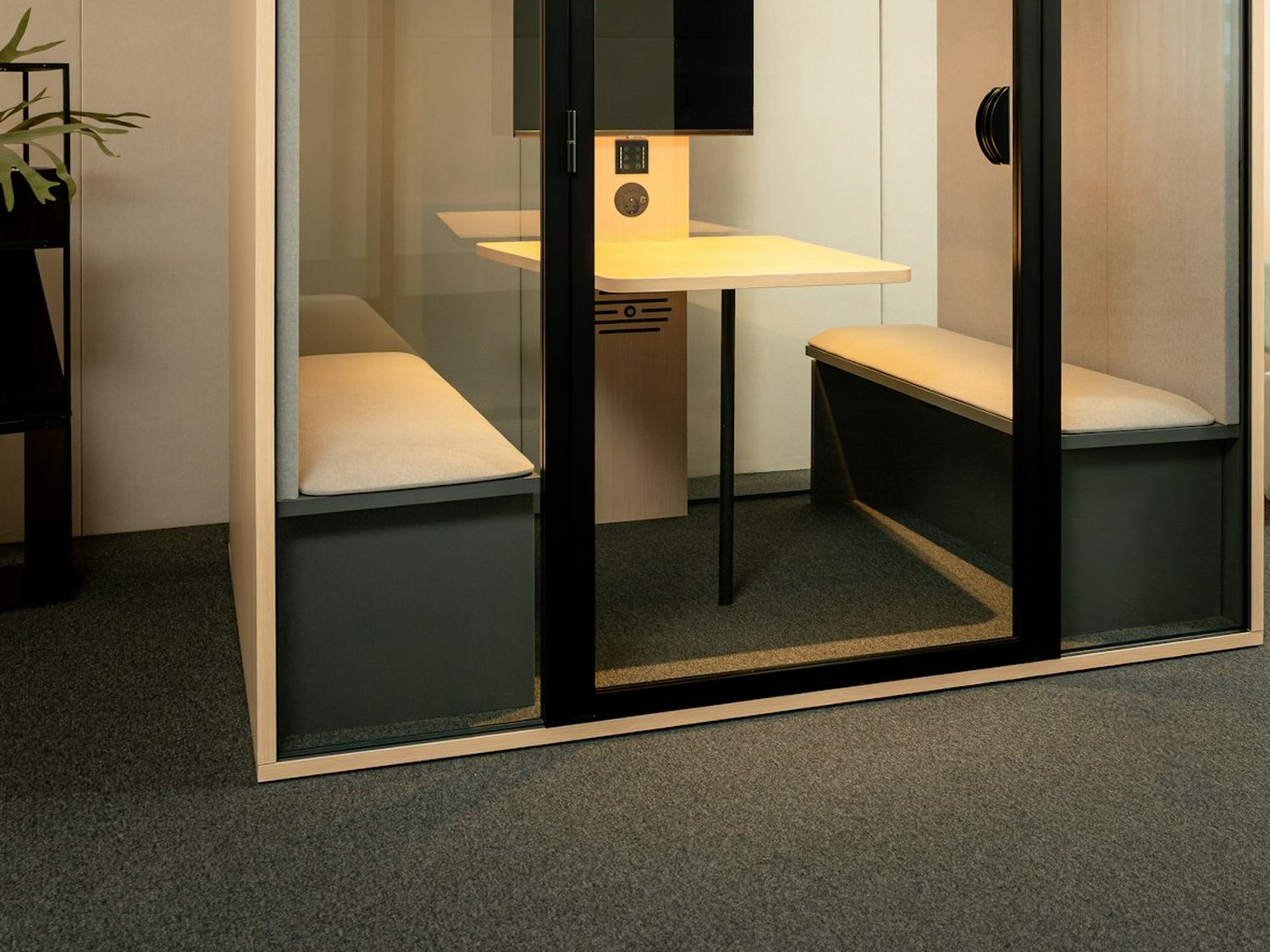 Cabine acoustique de bureau vitrée, avec banquettes et plan de travail.